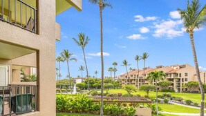 A hotel with a balcony, palm trees, and a well-maintained lawn. - Tranquil Courtyard View Condo w/Kitchen Updates, WiFi, Washer/Dryer–#7203 (KIHEI)