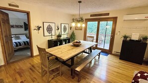 Ein Essbereich mit einem Holztisch und Bänken, einer kleinen Pflanze seitlich und einer Tür, die auf einen Balkon führt.