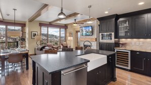A modern kitchen with a large island, dark cabinetry, and a view of the outdoors.