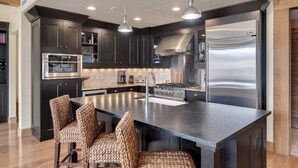 A modern kitchen with dark cabinetry, stainless steel appliances, and a central island with bar stools.