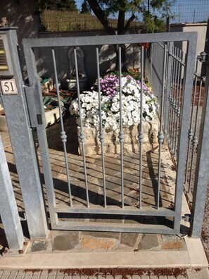 Secure gated entrance leads to a beautifully landscaped area with a stone pathway and vibrant flowers.