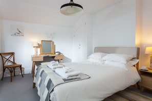 Een hotelkamer met een bed, een bureau met stoel, een lamp en een spiegel.