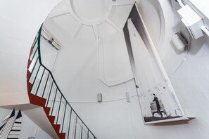 A spiral staircase with a handrail, a circular wall feature, and a black and white artwork.