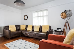 A modern living room with a sectional sofa, a floor lamp, and a patterned rug.