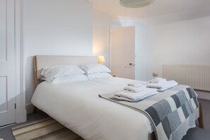 A hotel room with a bed, a radiator, a door, and a lamp.