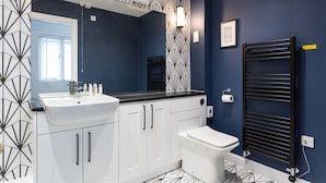 A modern bathroom with a white sink, a toilet, and a black towel rack.
