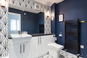 Een moderne badkamer met een wit wastafel, toilet en een zwarte handdoekhouder.
