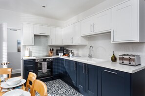 A modern kitchen with white cabinets, a stainless steel toaster, and a patterned floor.