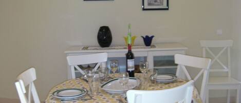 A dining table set with plates, glasses, and a bottle of wine.