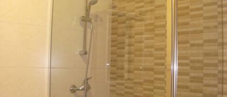 Eine Dusche mit Glastür und gefliesten Wänden.