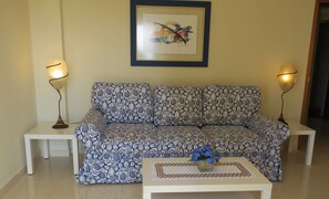 A living room with a patterned sofa, two side tables, a coffee table with a vase, and two floor lamps.