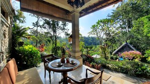A covered outdoor dining area with a table and chairs, surrounded by lush greenery and a view of the landscape. - Alam Indah Ubud (Ubud)