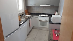 A compact kitchen with a refrigerator, stove, microwave, and sink.