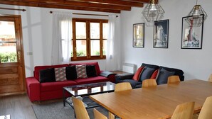 Een gezellige woonkamer met een rode bank, een houten eettafel en een groot raam.