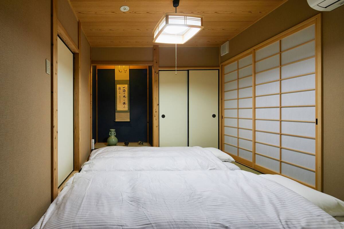 Una habitación tradicional japonesa con cama, puertas correderas y una lámpara colgante.