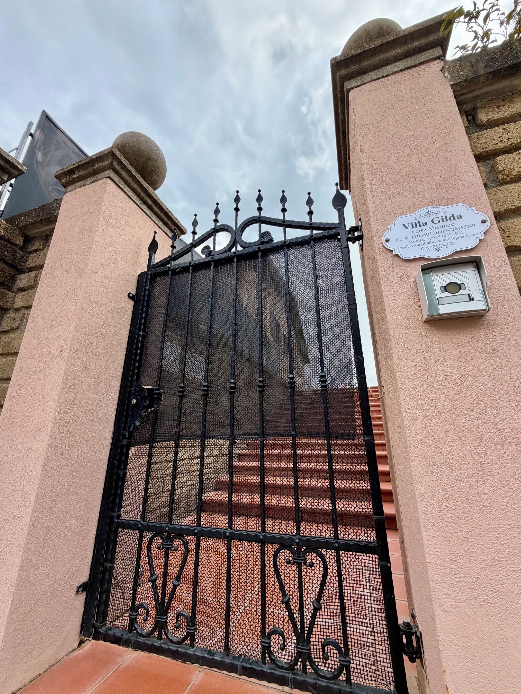 Un cancello carrabile con inferriata, una targa informativa e una telecamera di sicurezza.