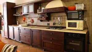 A kitchen with dark wooden cabinets, a built-in oven, a microwave, and a stove. - Villa Gilda Bracciano with private Pool & A/C (Bracciano, Italia)