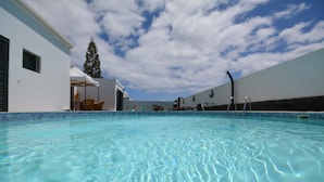 A swimming pool with clear water, surrounded by white buildings and a clear sky. - Villa Nirvan with Heated Pool (playa blanca, yaiza, lanzarote)