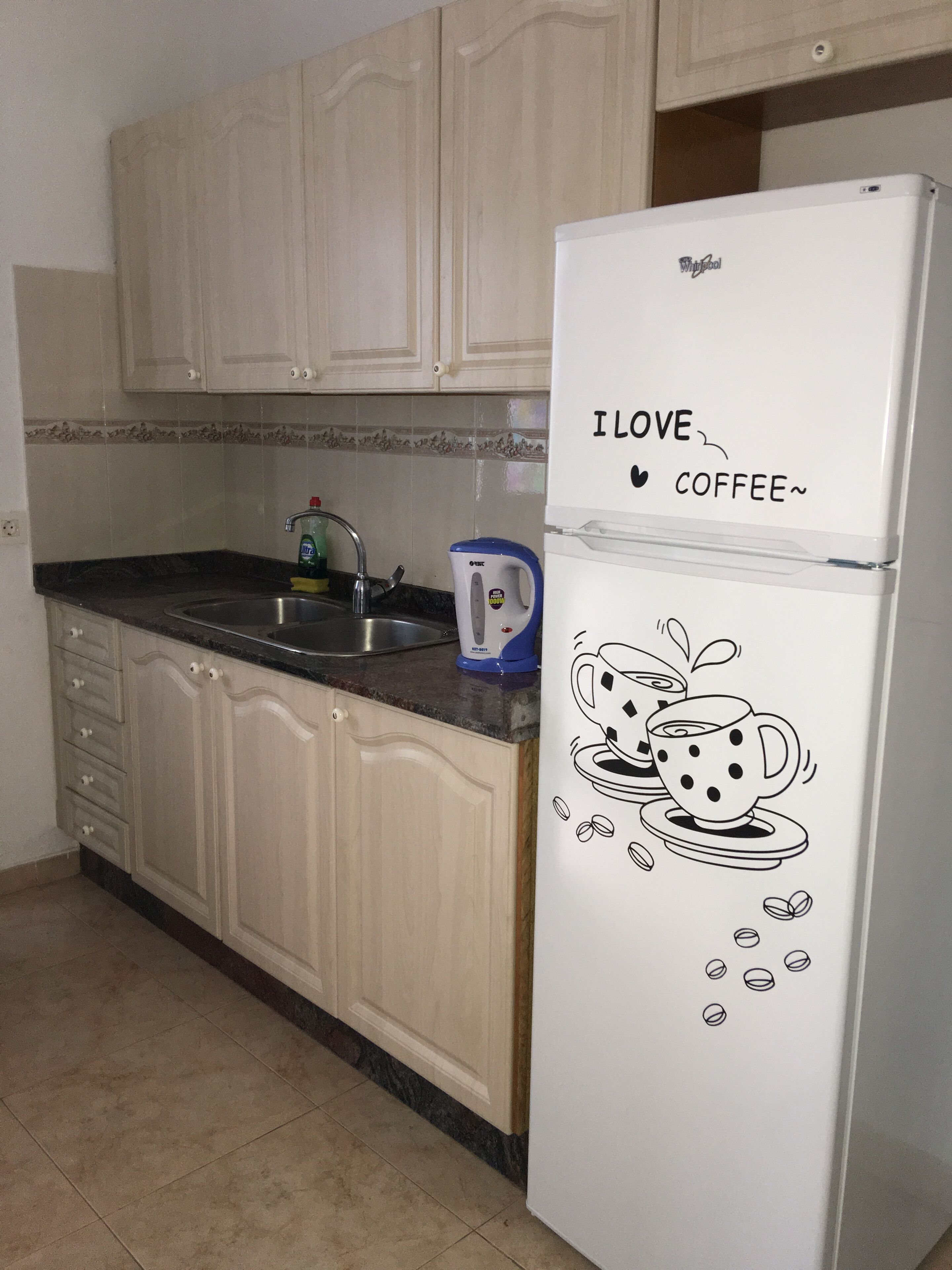 A kitchen with a refrigerator, a sink, and cabinets.