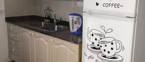 A kitchen with a refrigerator, a sink, and cabinets.