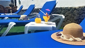 A beachside lounge area with blue lounge chairs, a table with drinks, and a straw hat. - Villa Nirvan with Heated Pool (playa blanca, yaiza, lanzarote)