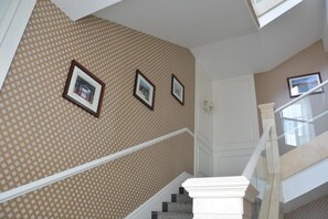 A staircase with a patterned wallpaper and framed pictures on the wall. - Mountain Villa Hotel (Chengde)