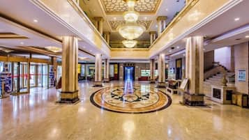 A spacious lobby with a central circular design, large columns, and a grand chandelier.