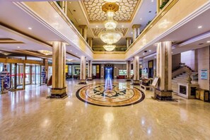 A spacious lobby with a central circular design, large columns, and a grand chandelier.