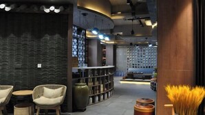 A modern interior with a curved seating area, a bookshelf, and a decorative vase. - Mountain Villa Hotel (Chengde)
