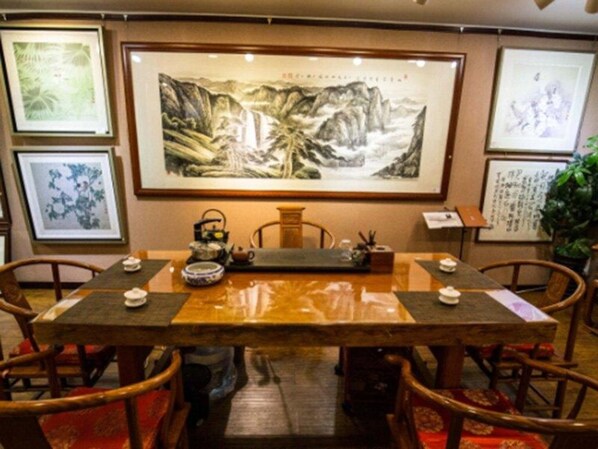 A traditional dining area with a wooden table, chairs, and artwork on the walls. - Mountain Villa Hotel (Chengde)