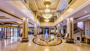 A spacious lobby with a central circular design, large columns, and a grand chandelier. - Mountain Villa Hotel (Chengde)