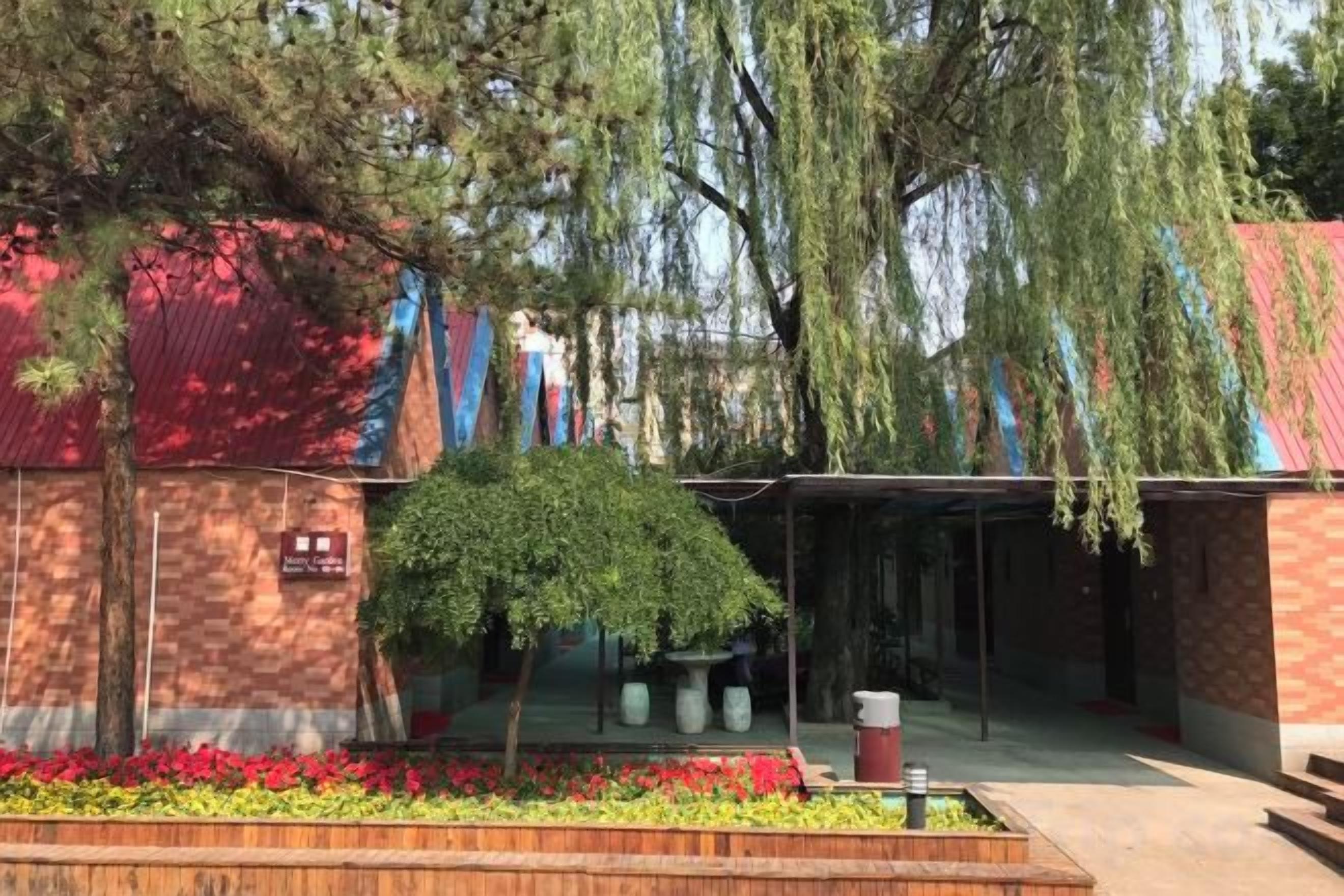 A building with a red roof, a covered outdoor area, and a small tree.