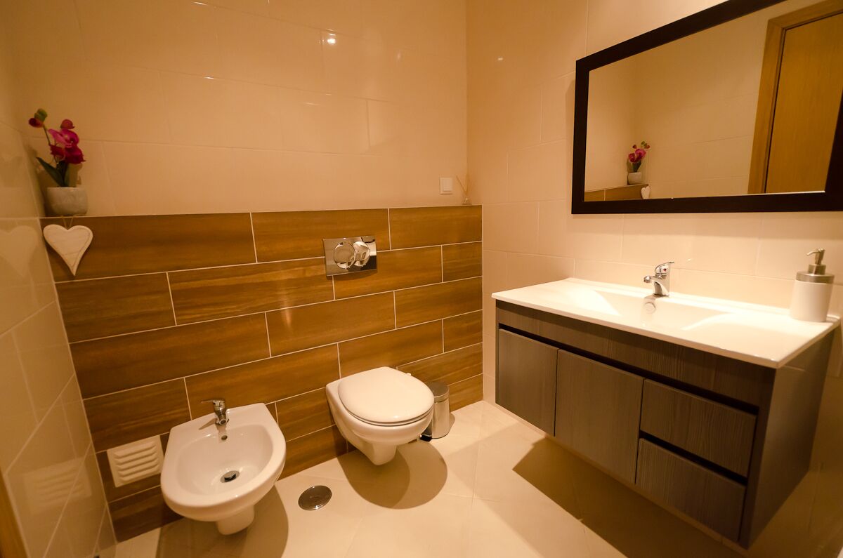 A modern bathroom with a bidet, toilet, and sink.