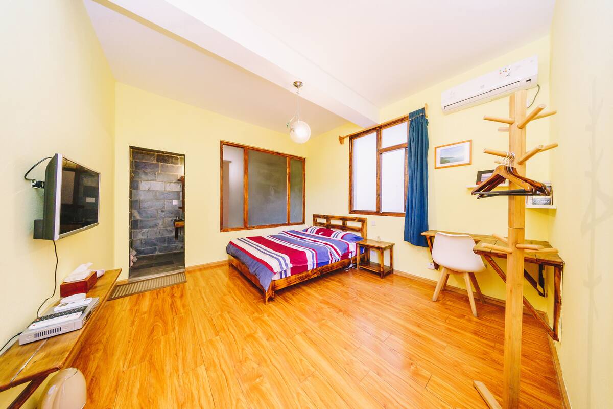 A bedroom with a bed, a desk, a chair, a TV, and a heater.