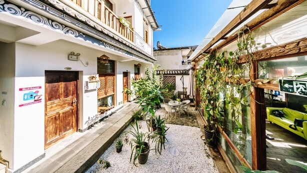 Un patio con un sendero de grava, plantas en macetas y un sofá verde.
