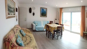 A living room with a sofa, a dining table with chairs, a TV, and a fireplace.