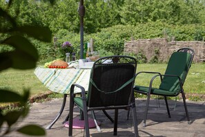 An outdoor dining area with a table set for two, surrounded by chairs. - Little Owls Barn, Preston Wynne, Herefordshire (Preston Wynne)
