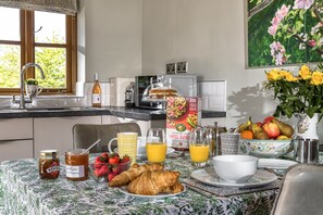 A breakfast setting with a table set for two, including croissants, strawberries, honey, and orange juice. - Little Owls Barn, Preston Wynne, Herefordshire (Preston Wynne)