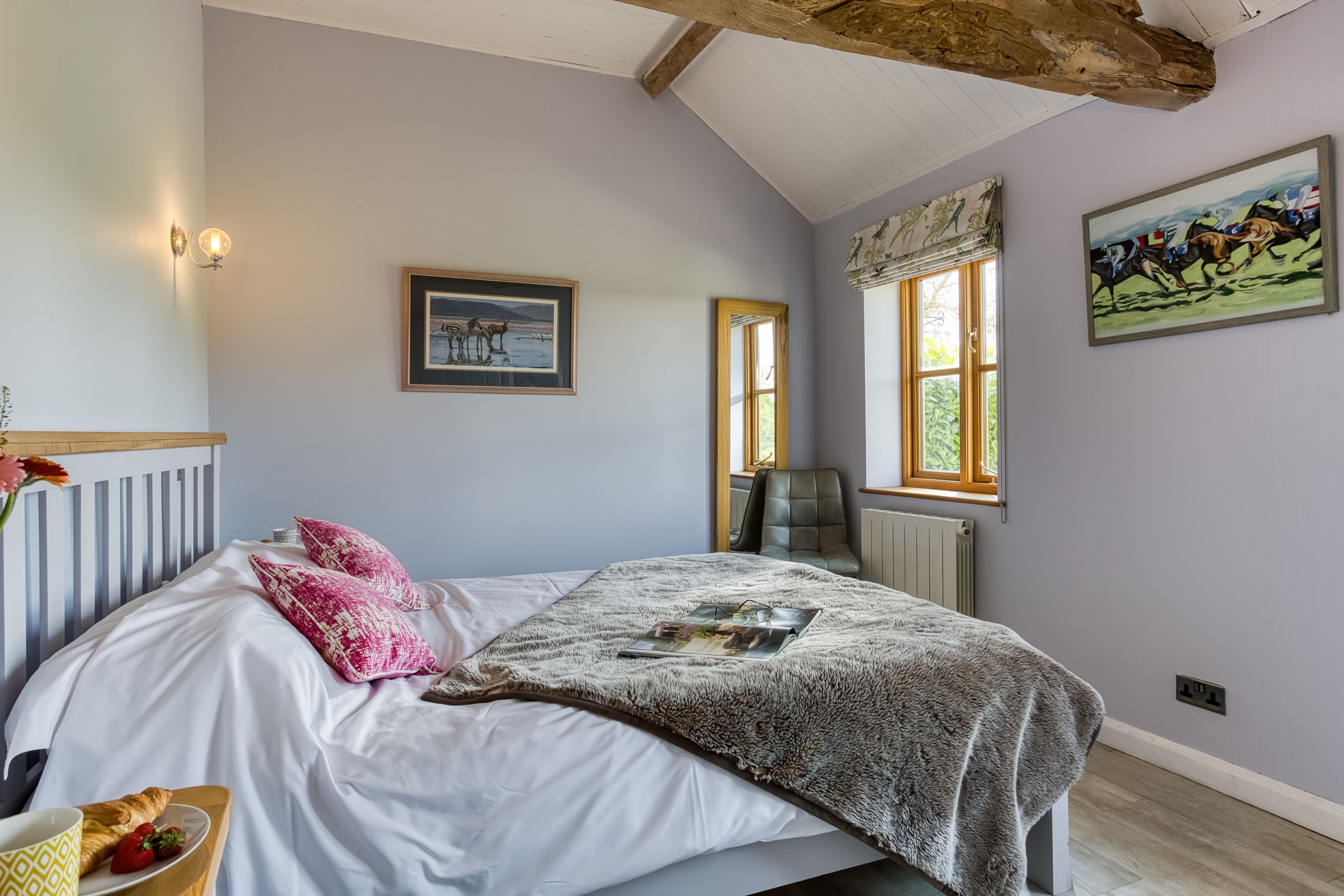 A bedroom with a bed, a window, a radiator, and a painting on the wall.