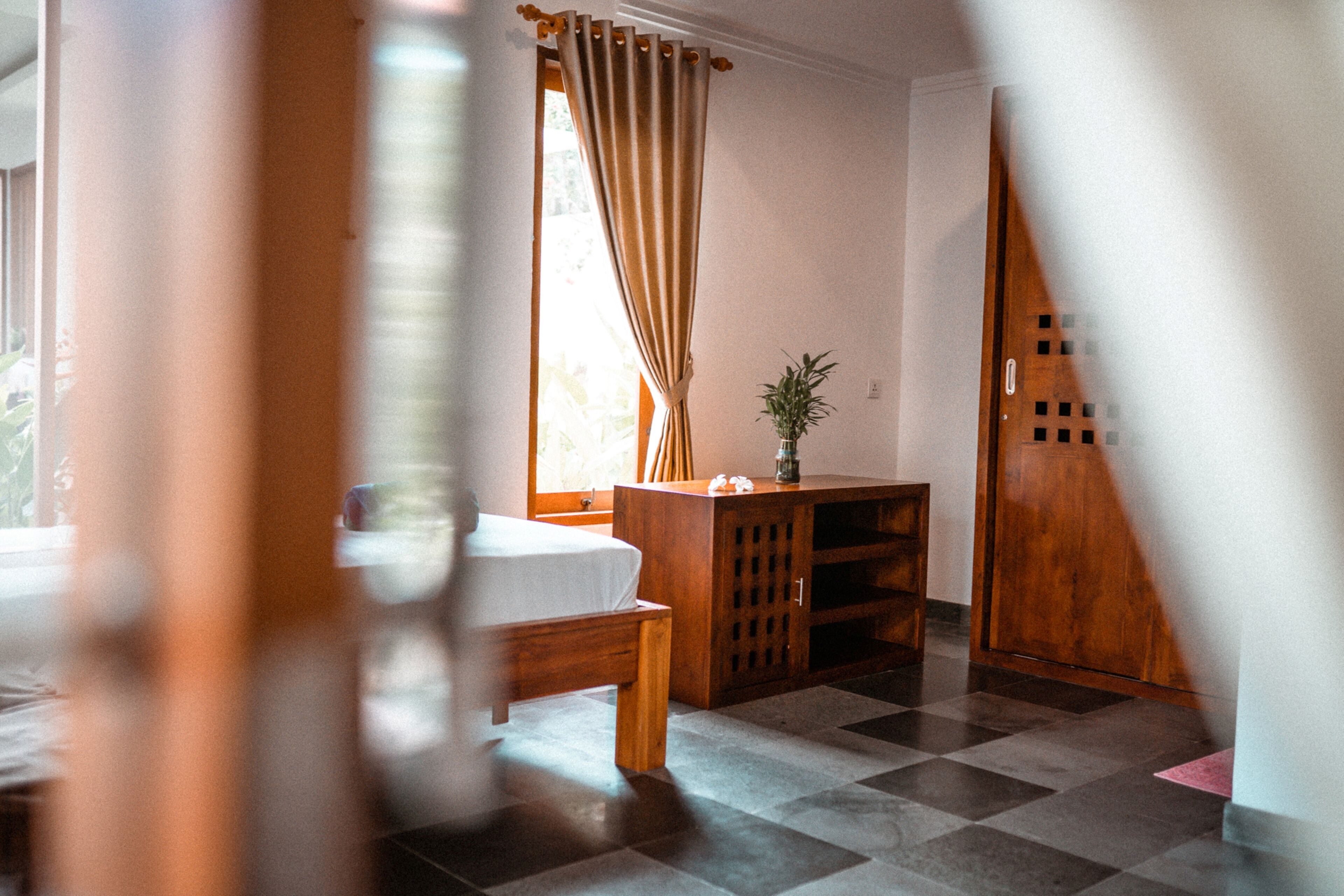 A room with a bed, a wooden cabinet, and a window with curtains.