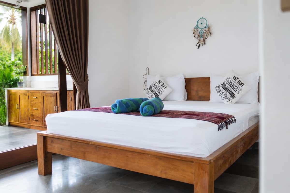 Ein Schlafzimmer mit einem hölzernen Bett, weiĂer BettwĂ€sche, einem TraumfĂ€nger und motivierenden Kissen.