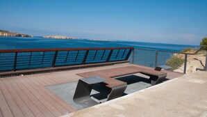 A deck with a view of the sea, featuring a railing and seating area. - GetawaysMalta - Seashells 2-bedroom Apartment in Bugibba (San Pawl il-Baħar)