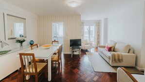 A modern living room with a sofa, TV, and dining area. - Casa da Calçada - 2nd Floor (Funchal)