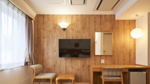 Een hotelkamer met houten paneelwanden, een flatscreen-televisie, een bureau met stoel, een kleine koelkast en twee bedden.