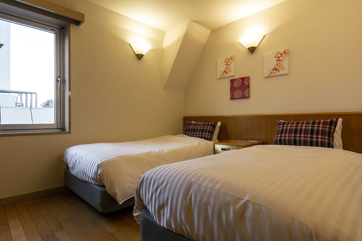 Una habitación de hotel con dos camas, un ventanal e iluminación empotrada.