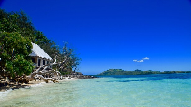 Ein Strandhaus mit freiem Blick auf den Ozean und einer entfernten Insel.