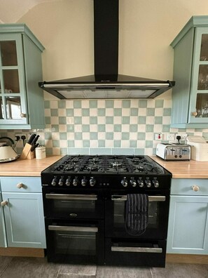 A kitchen with a black stove, a range hood, and light blue cabinets.