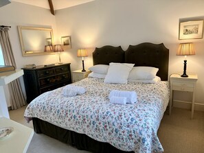 A neatly made bed with floral bedding, two bedside lamps, a dresser, and a mirror on the wall. - Ty Newydd, Bodnant Estate, Colwyn Bay, Conwy, Wales (Colwyn Bay)