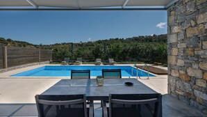 A covered outdoor area with a pool, stone wall, and seating. - Kalostous villa 4, Pool,Great location & Views (Agia Triada)