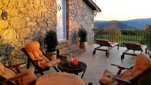 A covered patio with stone walls, outdoor furniture, and a view of the countryside. - Cute vacation house surrounded by green area (Buzet)